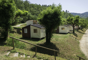 Canvas Mobile-Home Tithome al Flower Camping Mas de Champel in Francia, circondato da alberi e colline verdi.
