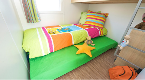 Kinderkamer in Canvas Mobile-Home Tithome met kleurrijk beddengoed en speelgoed bij Flower Camping Mas de Champel.