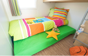 Kinderkamer in Canvas Mobile-Home Tithome met kleurrijk beddengoed en speelgoed bij Flower Camping Mas de Champel.