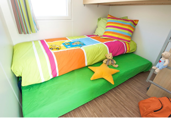 Cameretta nel Canvas Mobile-Home Tithome con biancheria colorata e giocattoli presso Flower Camping Mas de Champel.