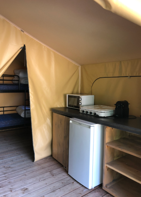 Binnenzicht van de Bali Safari Tent bij Flower Camping Mas de Champel met keuken en stapelbedden.