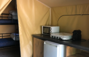 Interieur van de Bali Safari Tent bij Flower Camping Mas de Champel met keukentje en stapelbedden.