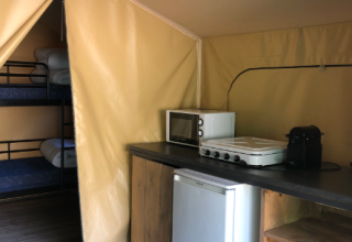Binnenzicht van de Bali Safari Tent bij Flower Camping Mas de Champel met keuken en stapelbedden.