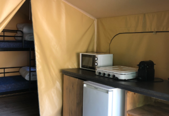 Binnenzicht van de Bali Safari Tent bij Flower Camping Mas de Champel met keuken en stapelbedden.