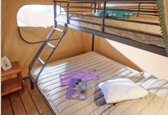 Indvendigt billede af Bali Safari-teltet på Flower Camping Mas de Champel med køjeseng og trægulv.