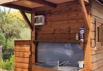 Outdoor-Holzküche mit Spüle am Bali Safari Zelt bei Flower Camping Mas de Champel in Frankreich