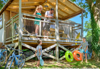 Famiglia che si gode una giornata estiva in un lodge CosyFlower Premium con bambini che giocano e biciclette fuori.