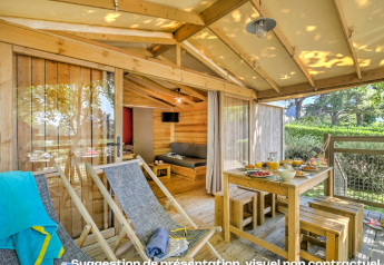 Terrazza in legno con tavolo da pranzo e sdraio al CosyFlower Premium Lodge, Flower Camping Mas de Champel, Francia.
