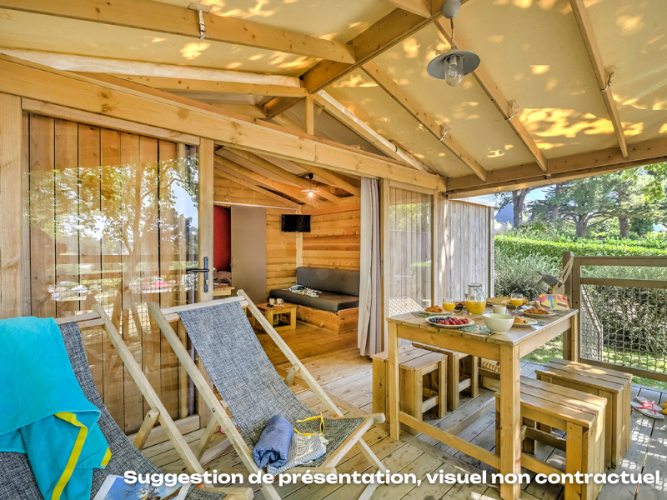 Gemütliche Holzterrasse mit Esstisch und Liegestühlen bei der CosyFlower Premium Lodge am Mas de Champel, Frankreich.