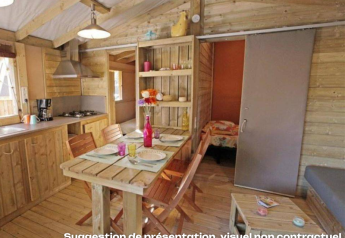 Interno di un'accogliente casetta in legno con cucina, zona pranzo e camera da letto al Mas de Champel, Francia.