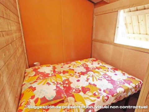 Kleine slaapkamer met kleurrijk beddengoed in een houten hut bij CosyFlower Premium, Flower Camping Mas de Champel, Frankrijk.
