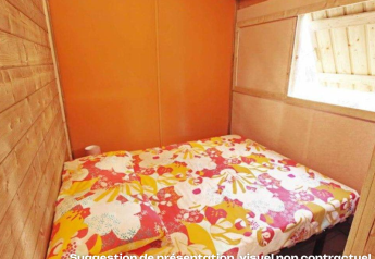 Piccola camera da letto con biancheria colorata in baita di legno al CosyFlower Premium, Flower Camping Mas de Champel, Francia.