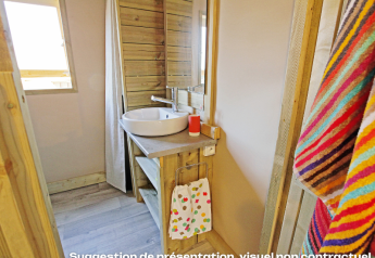Bagno con pareti in legno, lavandino rotondo e asciugamano colorato al Flower Camping Mas de Champel in Francia.