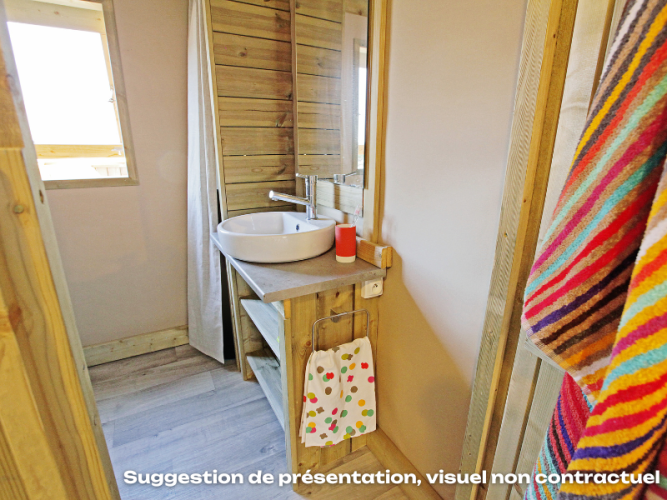 Bagno con pareti in legno, lavandino rotondo e asciugamano colorato al Flower Camping Mas de Champel in Francia.