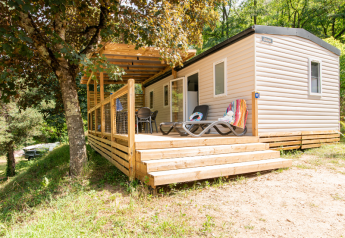Casa mobile moderna con terrazza in legno e lettini, immersa nel verde, ideale per rilassarsi all’aperto.