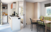 Modern mobile home with kitchen, dining area and sofa at Flower Camping Mas de Champel in France.