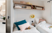Indvendigt udsyn af en mobilhome med et moderne køkken, åbent til terrassen, og et hyggeligt soveværelse.