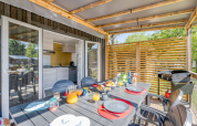 Buiteneethoek bij een glampingaccommodatie met gedekte tafel en zicht op moderne keuken binnen.