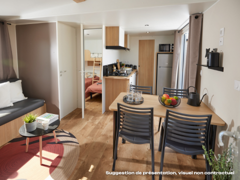 Lichte Homeflower Premium-lodge met keuken, eettafel, zithoek en slaapkamer zichtbaar op de achtergrond.