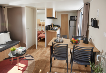 Moderne Homeflower Premium-lodge med åbent køkken, spiseplads, sofa og synligt soveværelse.