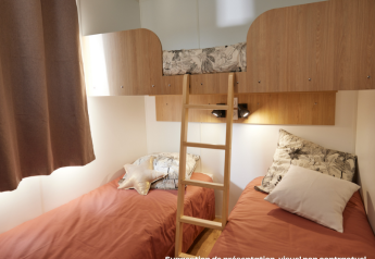 Glampingkamer met twee eenpersoonsbedden, een bovenste stapelbed en een houten ladder in het midden.