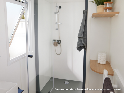 Moderne badkamer met douche, handdoek, plankjes en raam in een Vlaamse glamping accommodatie.