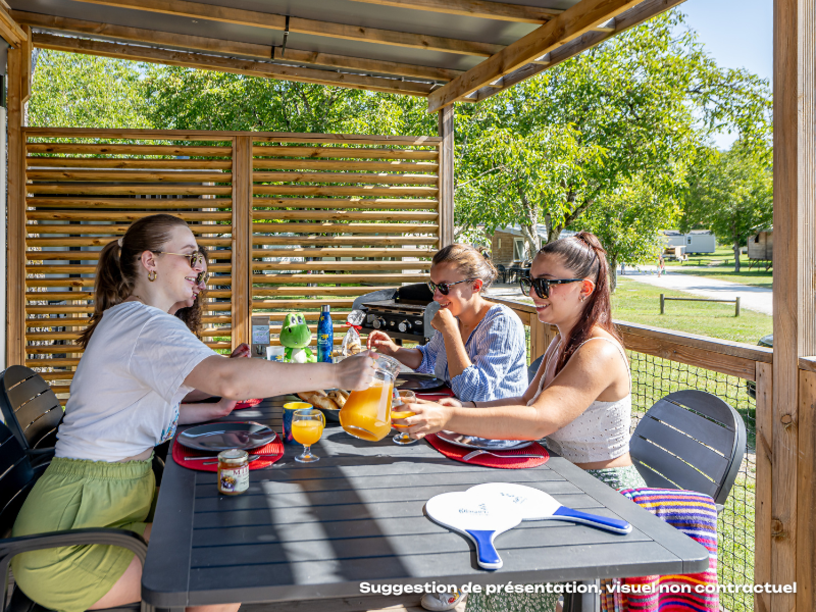 Drie vrouwen ontbijten buiten in de Homeflower Premium lodge bij Flower Camping Mas de Champel in Frankrijk.