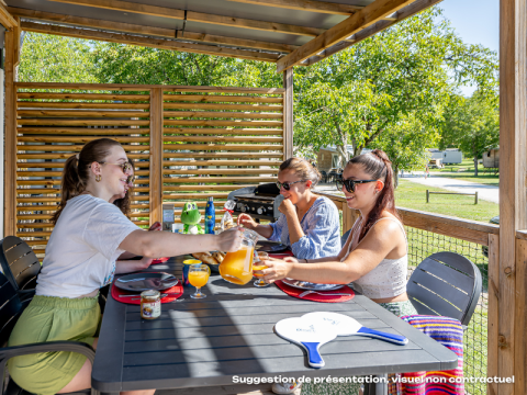 Drie vrouwen genieten van ontbijt op het terras van Homeflower Premium bij Flower Camping Mas de Champel in Frankrijk.