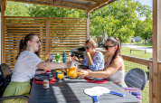 Drie vrouwen ontbijten buiten in de Homeflower Premium lodge bij Flower Camping Mas de Champel in Frankrijk.