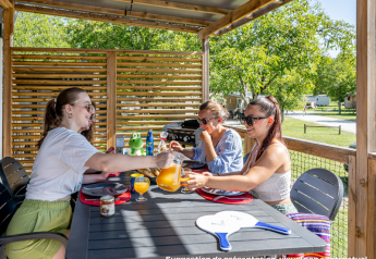Tre kvinder nyder morgenmad udendørs på Homeflower Premium lodge ved Flower Camping Mas de Champel i Frankrig.