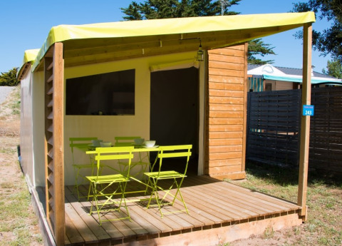 Terrasse extérieure de la cabane Funflower Standaard avec meubles verts et sol en bois sur un camping.