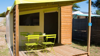 Terrasse der Funflower Standaard-Hütte mit hellgrünen Gartenmöbeln und Holzboden auf Campingplatz.