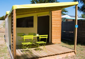 Veranda della cabina Funflower Standaard con mobili da giardino verdi e pavimento in legno su un campeggio.