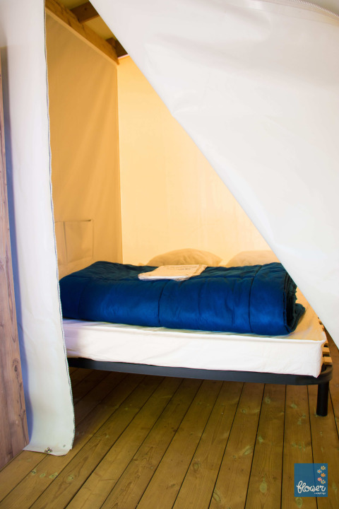 Interieur met een bed in de Funflower Standaard hut bij Flower Camping Les Paludiers, Frankrijk.