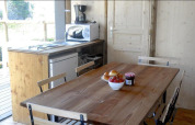 Kitchen and dining table in a safari tent, featuring wooden furniture, appliances, and fruit on table.