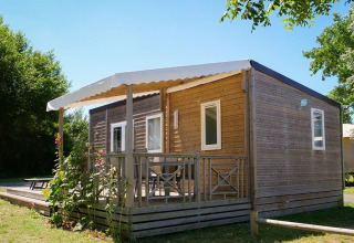 Lodge Stacaravan Premium au Flower Camping Les Paludiers en France, entouré de verdure et fleurs.