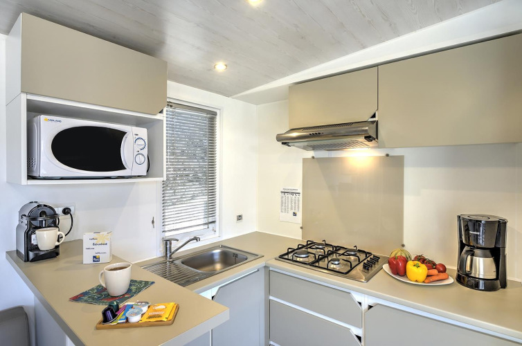 Modern kitchen in Stacaravan Premium lodge featuring gas stove, microwave, coffee makers, and fresh veggies.