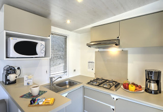 Cuisine moderne de la Stacaravan Premium lodge avec plaque de cuisson, micro-ondes, cafetières et légumes frais.