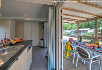 Binnenzicht van een chalet met keuken en toegang tot een overdekt terras met een gedekte tafel.