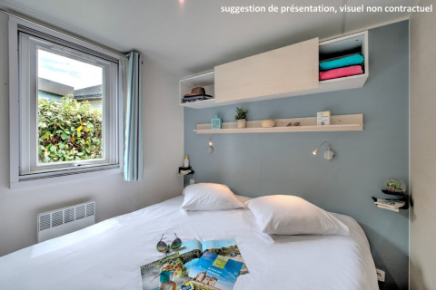 Helles gemütliches Schlafzimmer in einer Hütte mit Doppelbett, Fenster und dekorativen Wandregalen.