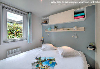 Helles gemütliches Schlafzimmer in einer Hütte mit Doppelbett, Fenster und dekorativen Wandregalen.