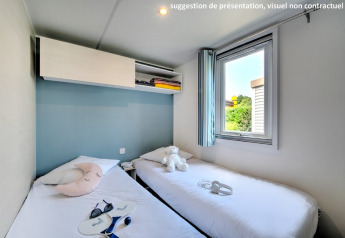 Knusse hut met twee eenpersoonsbedden, blauwe wand, raam en sfeervolle vakantiedecoratie.