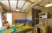 Interior view of Sweetflower op palen Premium lodge at Flower Camping Les Paludiers in France, showing kitchen and dining area.