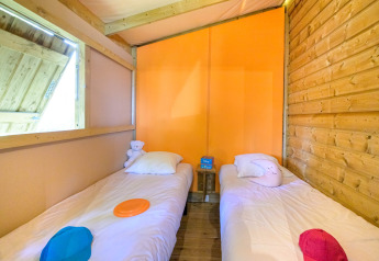 Værelse med to enkeltsenge og farverige vægge i et glamping-sted med trævægge og hyggelig stemning.