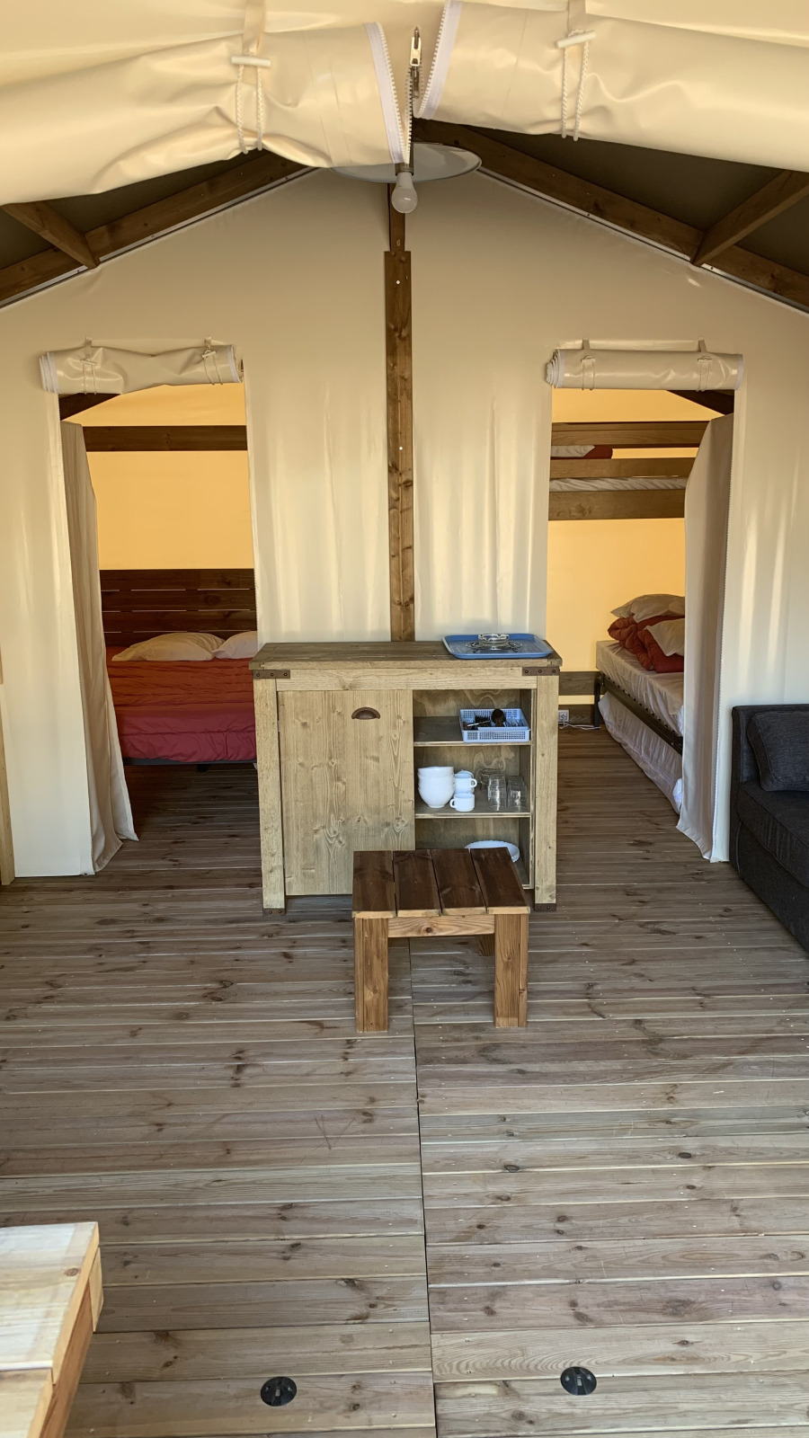Interieur van safari tent Freeflower Standaard bij Flower Camping Le Bel Air, Frankrijk, met houten meubels.