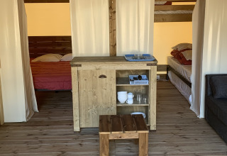Binnenkant van een Freeflower Standaard safaritent op Flower Camping Le Bel Air, met houten meubels en bedden.