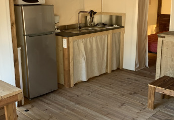 Interior de la tienda safari Freeflower Standaard en Flower Camping Le Bel Air, Francia, con cocina equipada.