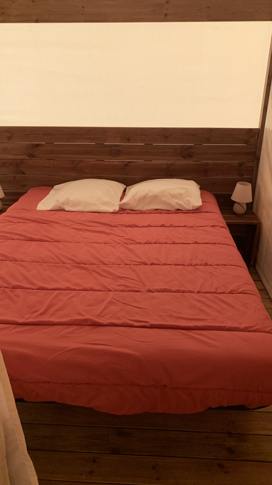 Bed met rood dekbed en twee witte kussens in safaritent bij Flower Camping Le Bel Air, Frankrijk.