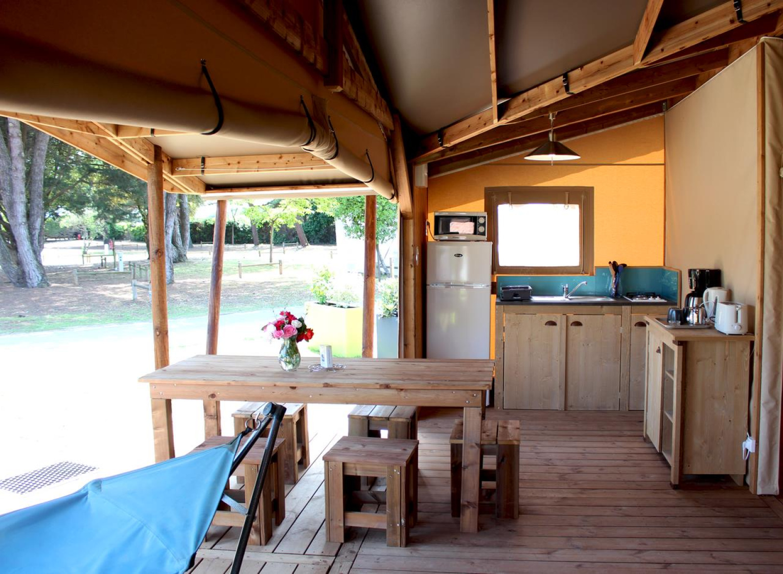 Interieur van het Ecolodge Cotton Comfort safaritent met houten meubels en keuken bij Flower Camping Le Bel Air in Frankrijk.