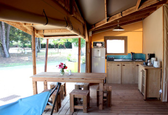 Indretning af Ecolodge Cotton Comfort safaritelt med træmøbler og køkken ved Flower Camping Le Bel Air i Frankrig.